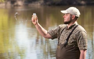 Water Quality Program Manager Ryan O'Donnell collects a water sample